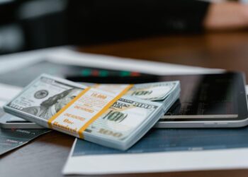 Stack of U.S. dollar bills on a tablet displaying financial charts