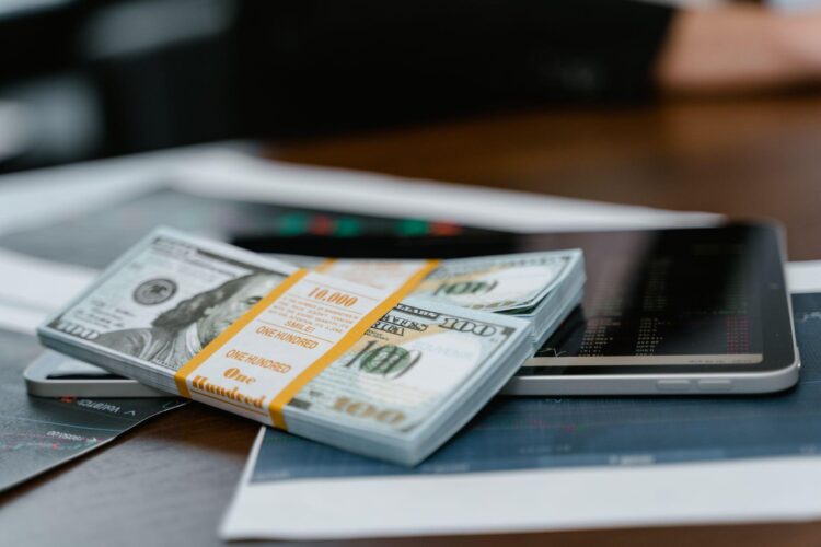 Stack of U.S. dollar bills on a tablet displaying financial charts